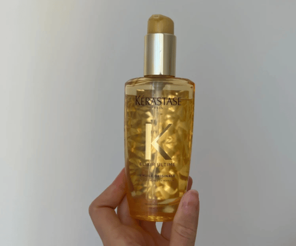 Woman's hand holding Kerastase Elixir Ultime Original Hair Oil
