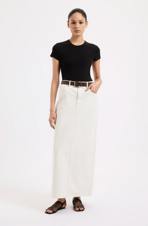 A model wears a white denim maxi skirt from Nudy Lucy.