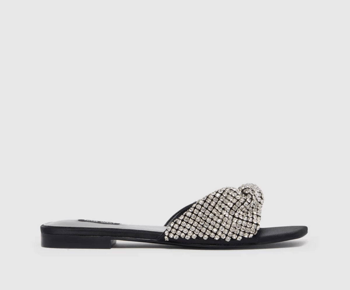 A pair of black, backless slip-on flats with a diamante-studded twisted strap.