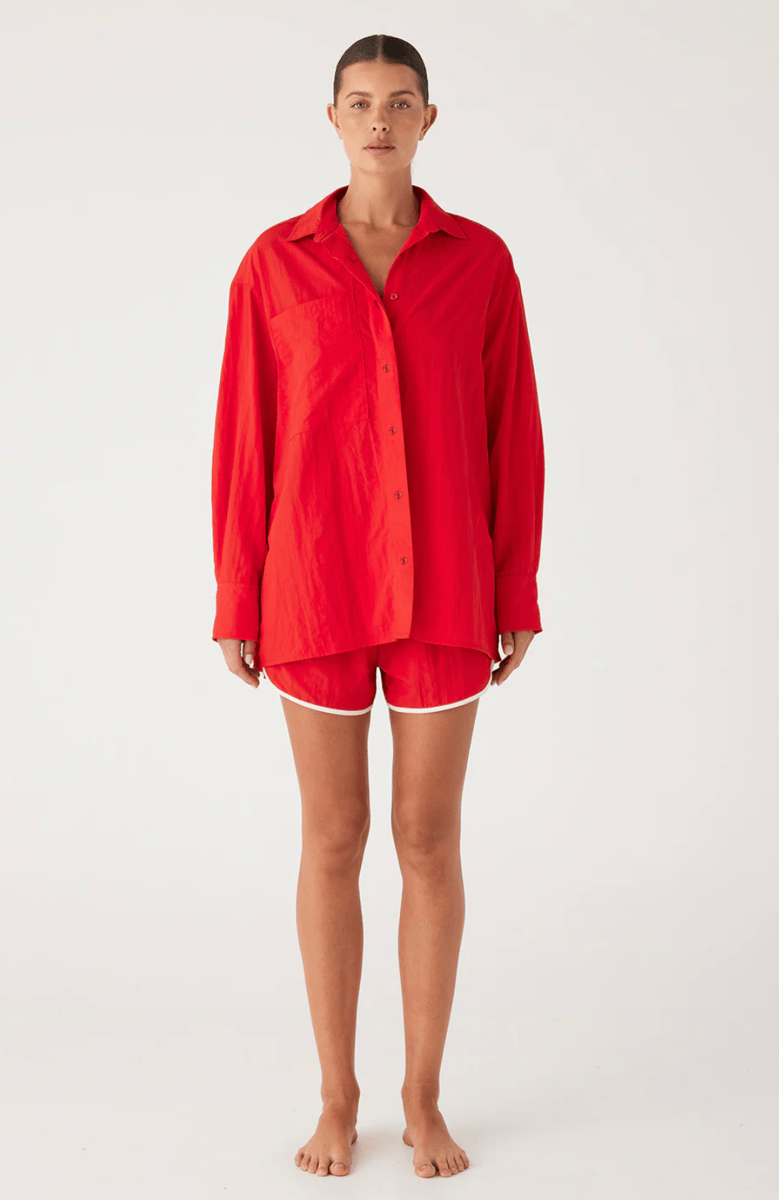 An oversized red silky shirt paired with matching short shorts.