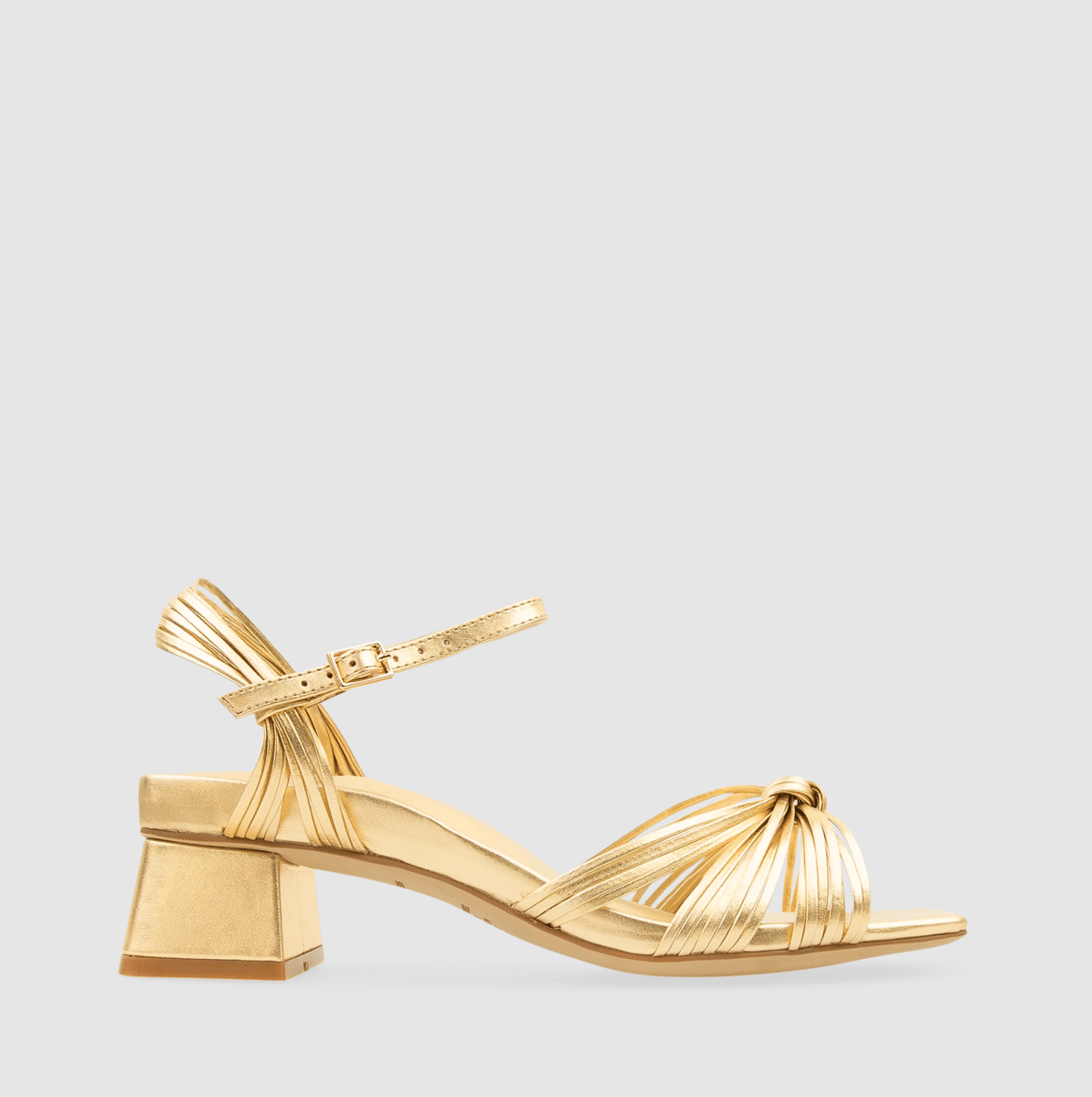 A pair of gold metallic short block heel sandals with woven knot detail at the front.