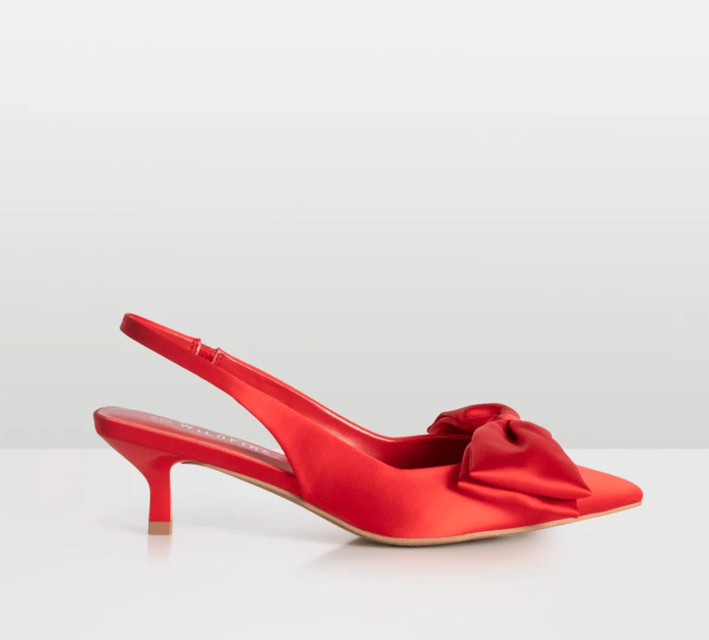 A red satin kitten heel slingback with a bow on the front.