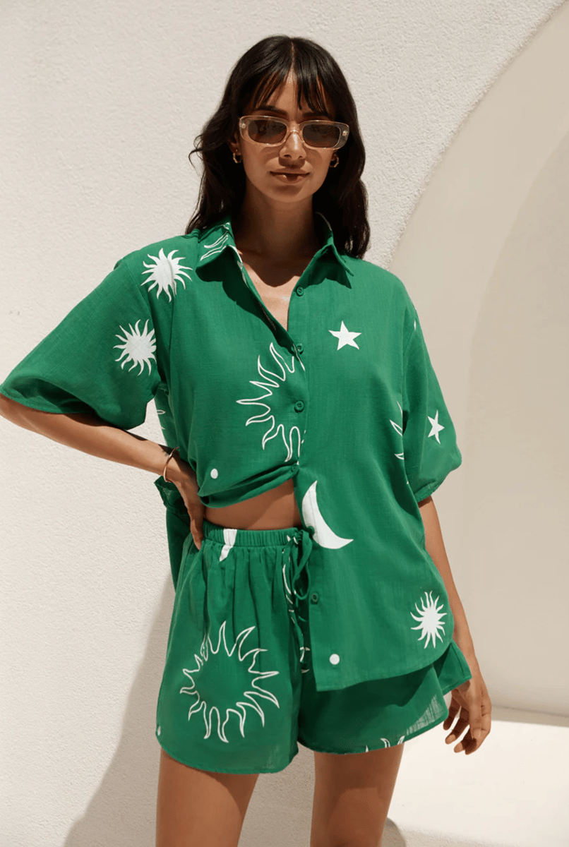 A green shirt and shorts set with a white graphic sun print.