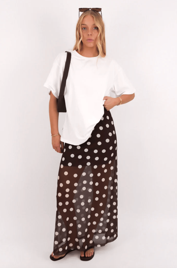 Model wears a semi-sheer polka dot maxi skirt in chocolate brown and cream.