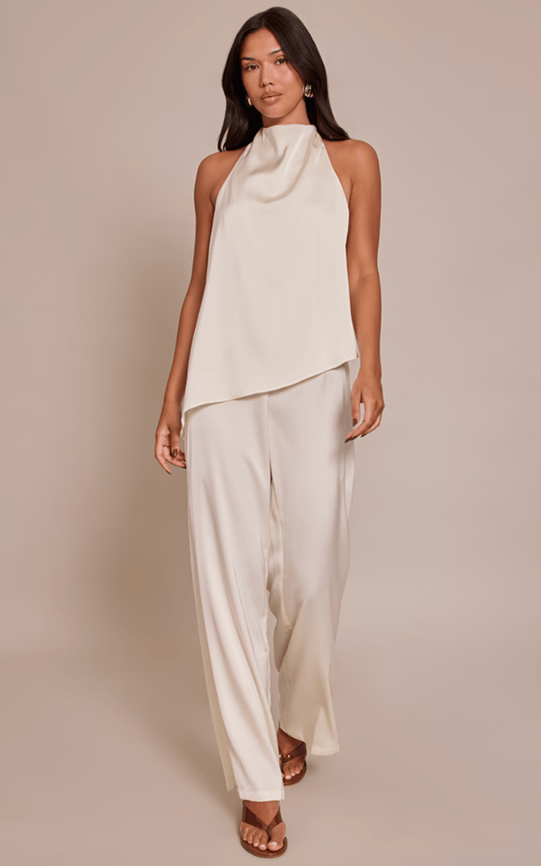 Model wearing cream satin halterneck jumpsuit.