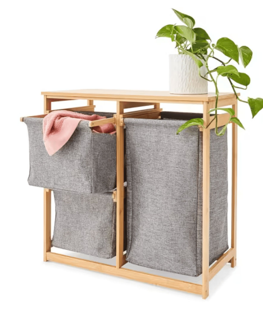 A grey laundry hamper with three baskets set in a wood frame.