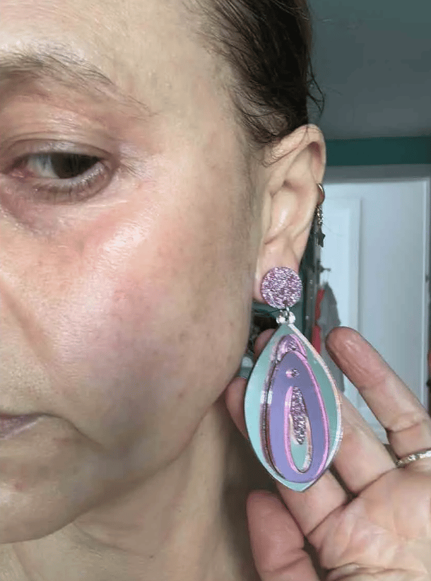 Mia Freedman wearing a pair of silver and purple vulva-shaped drop-down earrings.