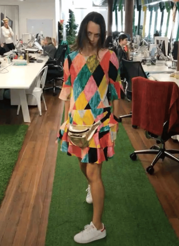 Mia Freedman wearing a bold colourful printed dress, a pair of white sneakers and a gold bum bag.