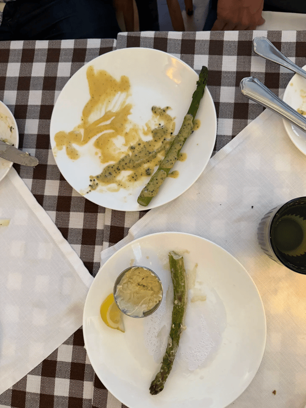 A picture of asparagus on a plate with sauce, and a second without sauce.