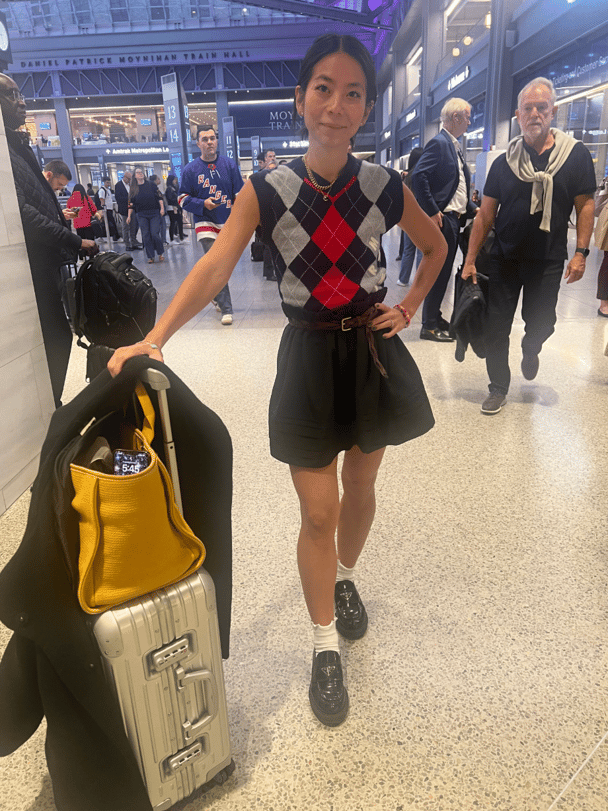 Woman stands with her suitcase and bags at train station.