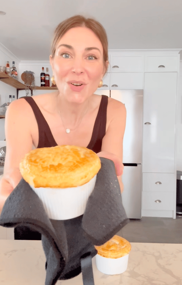 A woman takes individual beef stroganoff pot pies out of the oven.