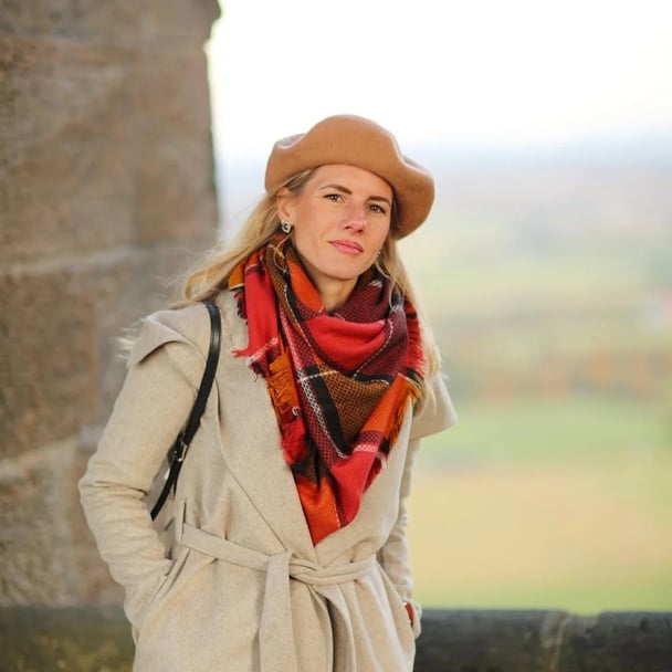 Woman wearing a beret, a red scarf and a coat.