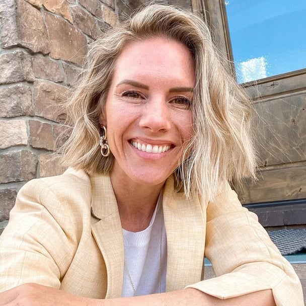 A woman with short hair wearing a beige blazer.