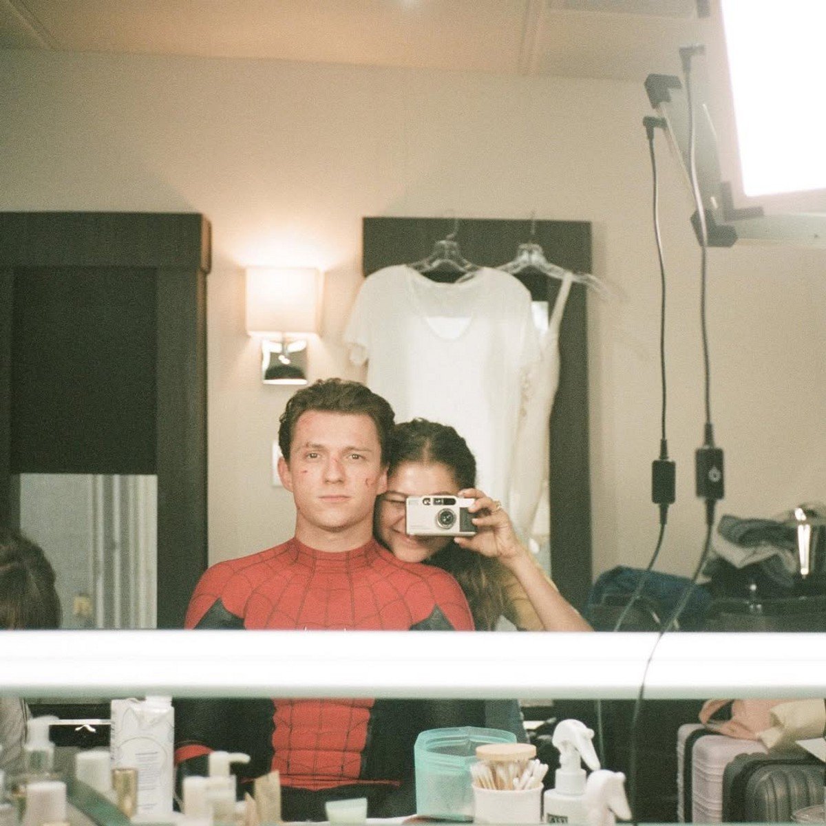 Tom Holland wearing his spiderman outfit, and Zendaya takine a mirror selfie of them. 