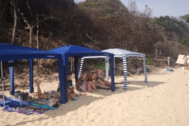 Family under three Cool Cabanas on the beach.