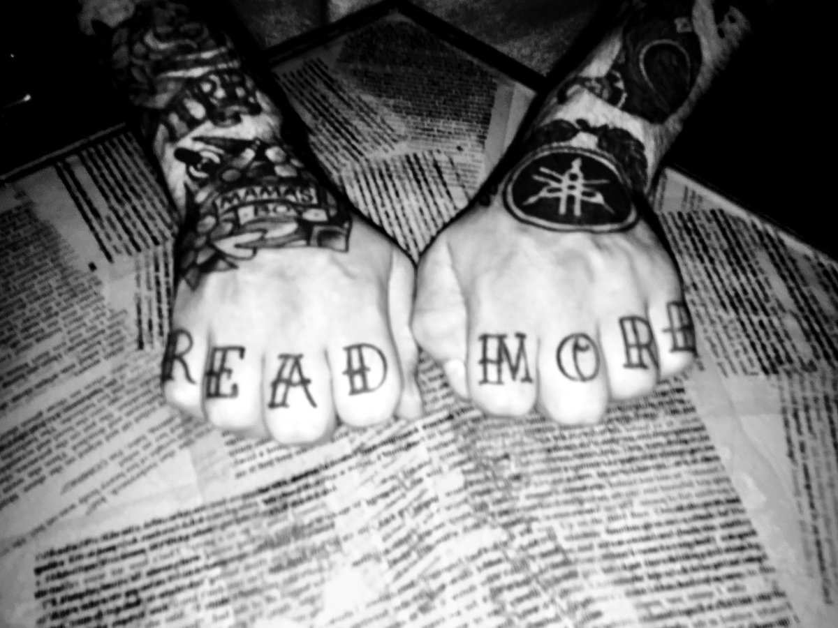 A man shows knuckles, which has 'READ MORE' tattooed across it.