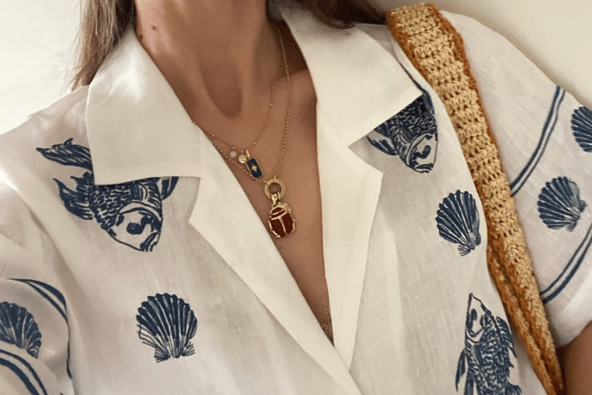 A close-up photo of a woman in layered gold charm necklaces.