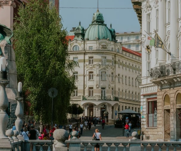 A lively picture of the Ljubljana streets, in the daytime, with the old architectural buildings in the background.