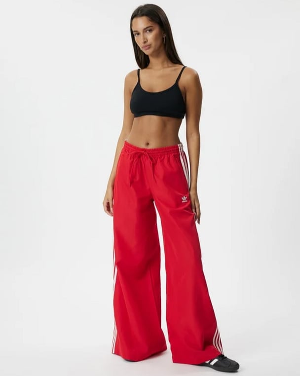 woman wearing red adidas tracksuit pants