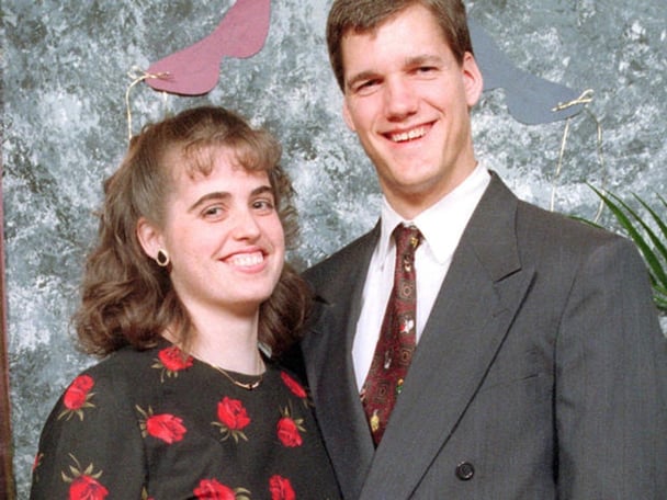 Couple Amy and Stephen Allwine pose in front of a grey background.