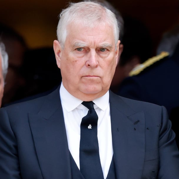 prince andrew with white hair in a black blazer, waistcoat, tie and white shirt.