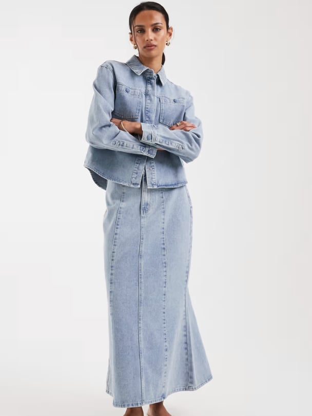 Woman wearing long-sleeved ligh wash denim jacket and a high-waisted, ankle-length denim maxi skirt from asos.