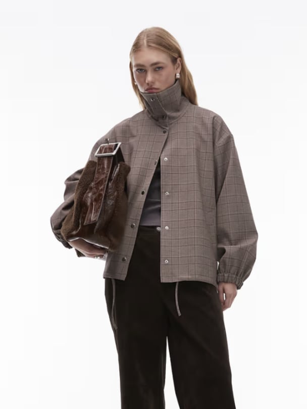 Model in funnel neck brown jacket.