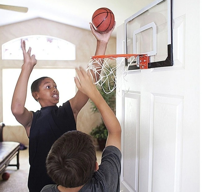 boys playing with a mini basketball hoop on a door 