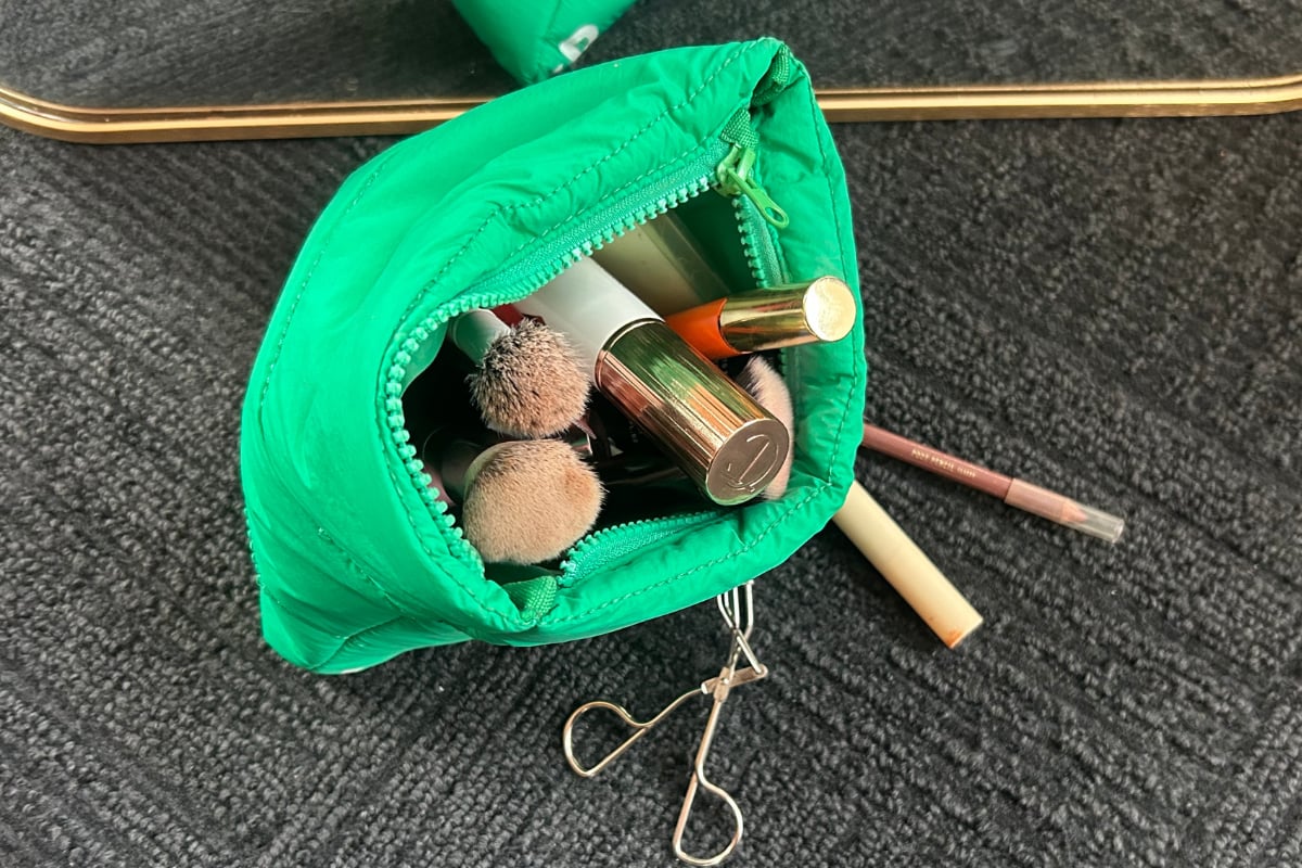 Green beauty bag with makeup inside.