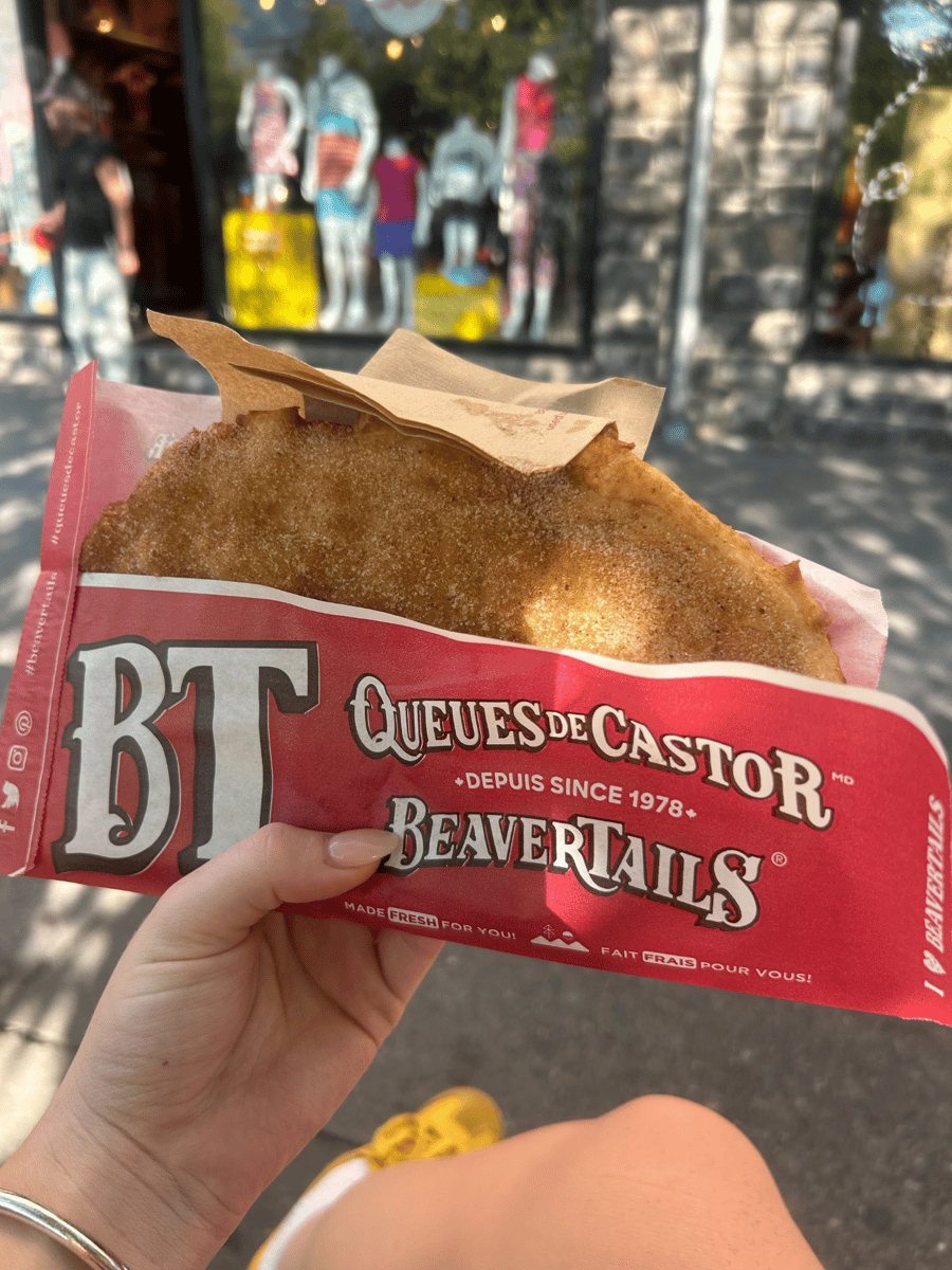 Lucy holding a cinnamon covered BeaverTail in red wrapping.