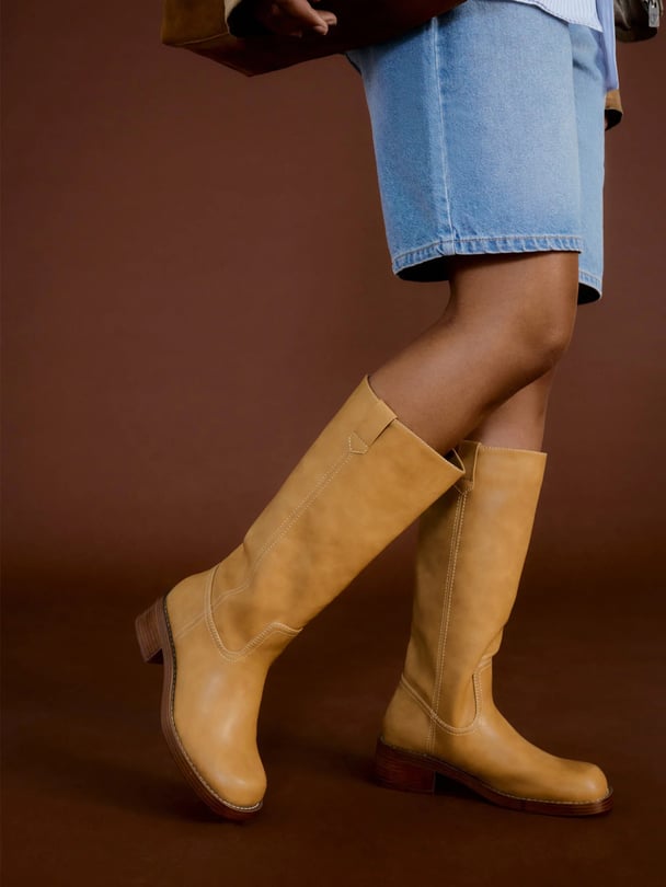 Model's legs wearing Bett's boots in banana colour with denim shorts.