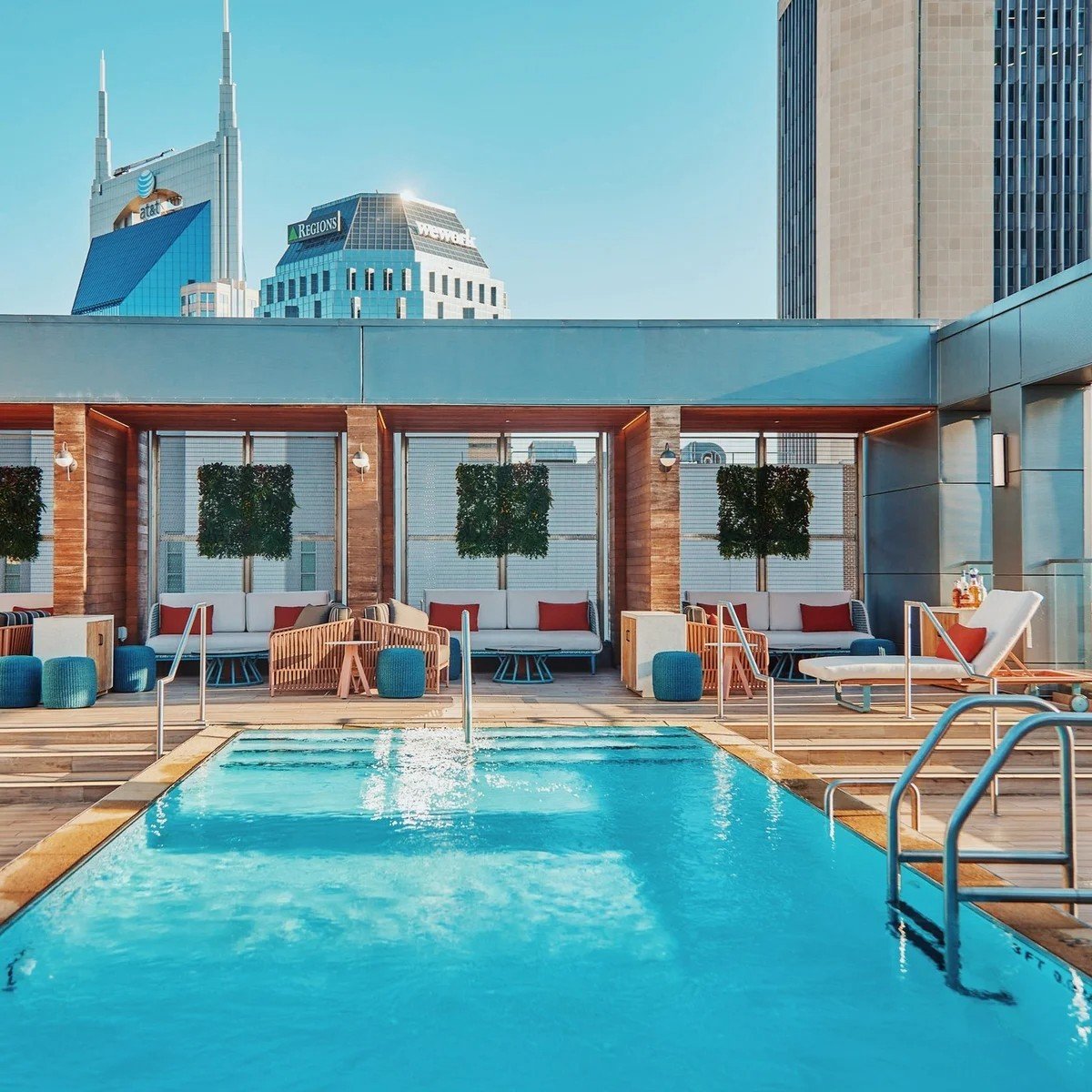 The rooftop pool at Bobby Nashville surrounded by loungechairs with skyscrapers behind.