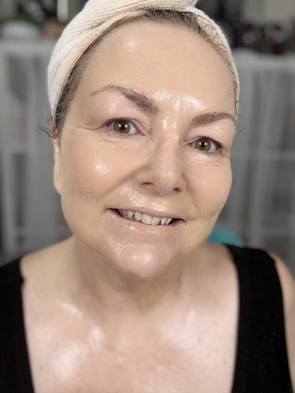 Teresa using a hydrating setting spray to drench her face after applying powder.