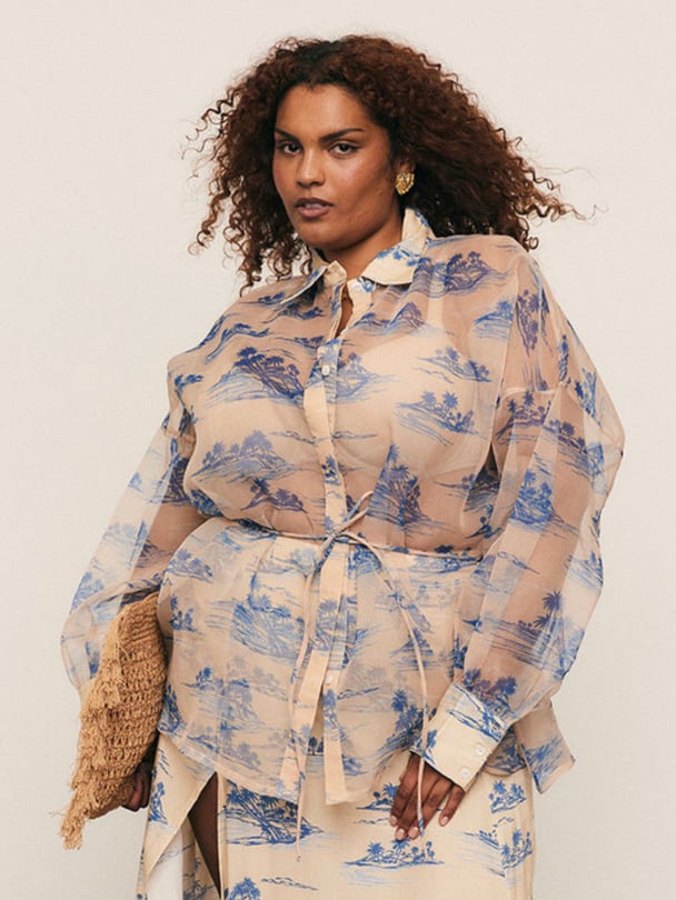 Model posing in sheer blouse with blue palm tree design.