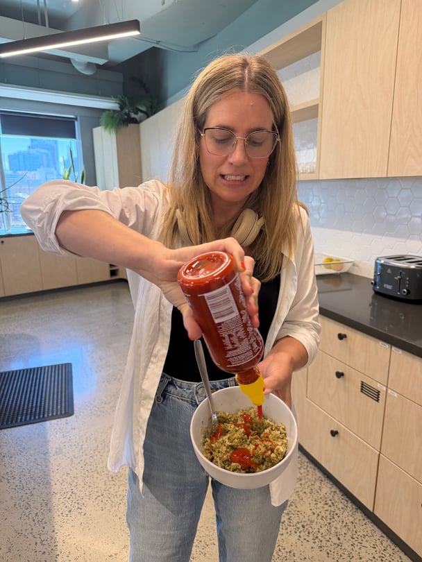 woman putting hot sauce on boy kibble in a kitchen