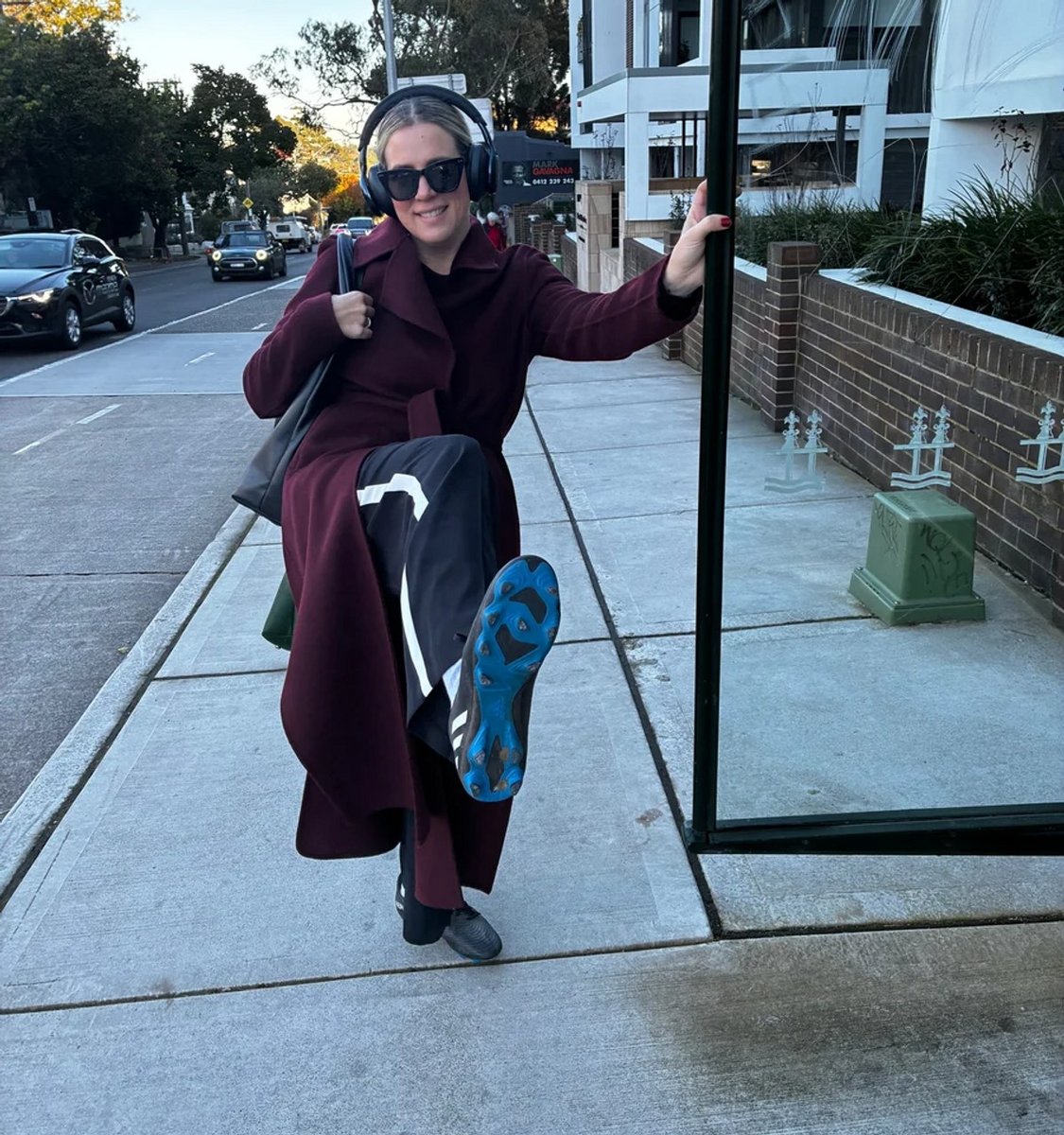 woman at a bus stop wearing football boots.