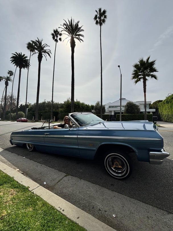 A photo of a tourist in a classic '64 Chevrolet Impala convertible as part of the Oscars Lowride Tour in LA.