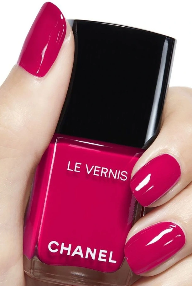 lady holding Chanel nailpolish with red pink nailpolish 