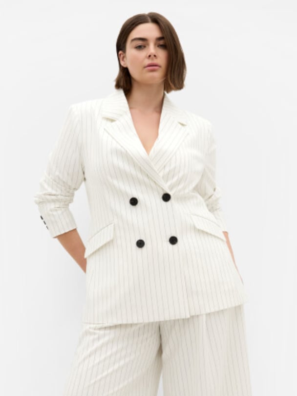 Model in black and white pinstripe blazer and pants set.