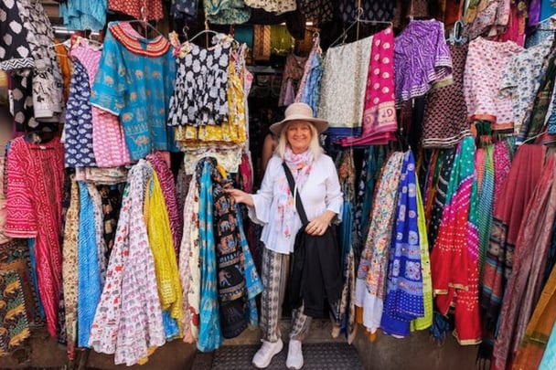 Jo in an Indian marketplace with rows of colorful saris.