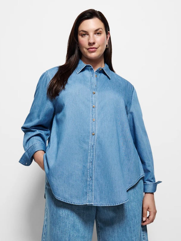 Model in long sleeve light wash denim shirt.