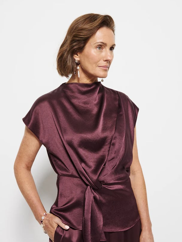 Model in wine-coloured silk sleevless blouse with tie waist.