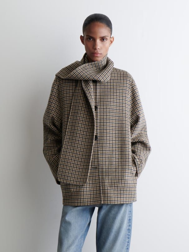 Model wearing a gingham coat with in-built scarf.