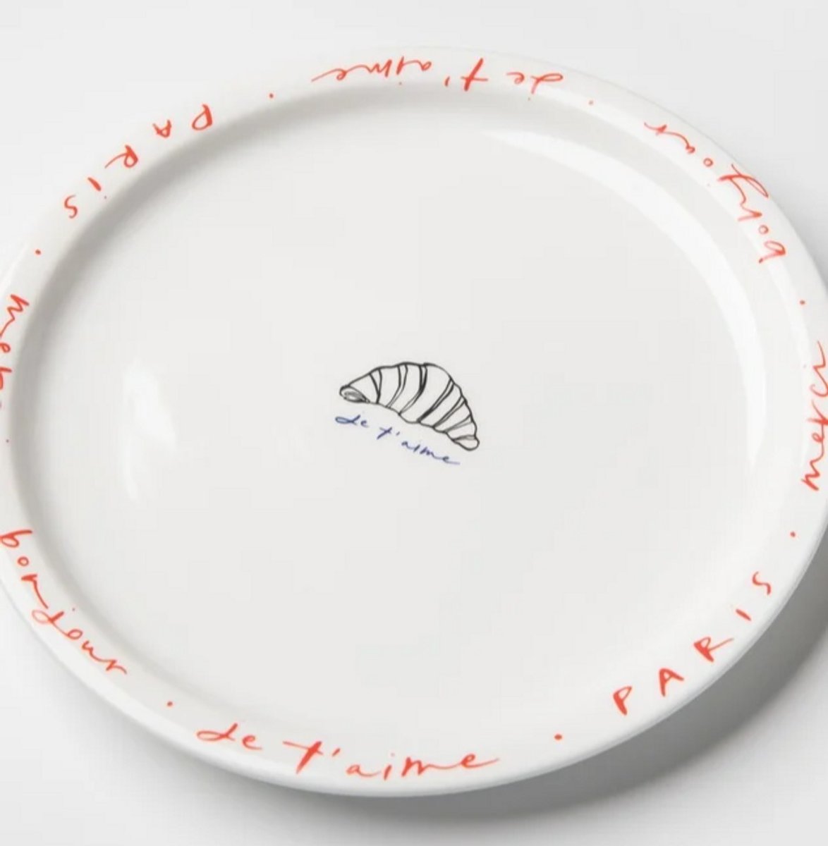 A french inspired plate with a picture of a criossaint and french writing 