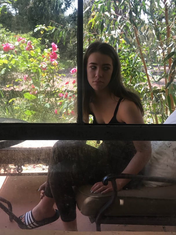 Darcie sitting outside as a teenager.