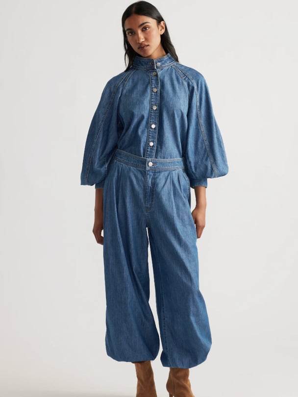 Woman wearing high-neck denim blouse with a button-down front and a high-waisted