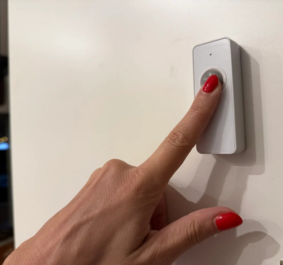woman ringing a doorbell with red nails 