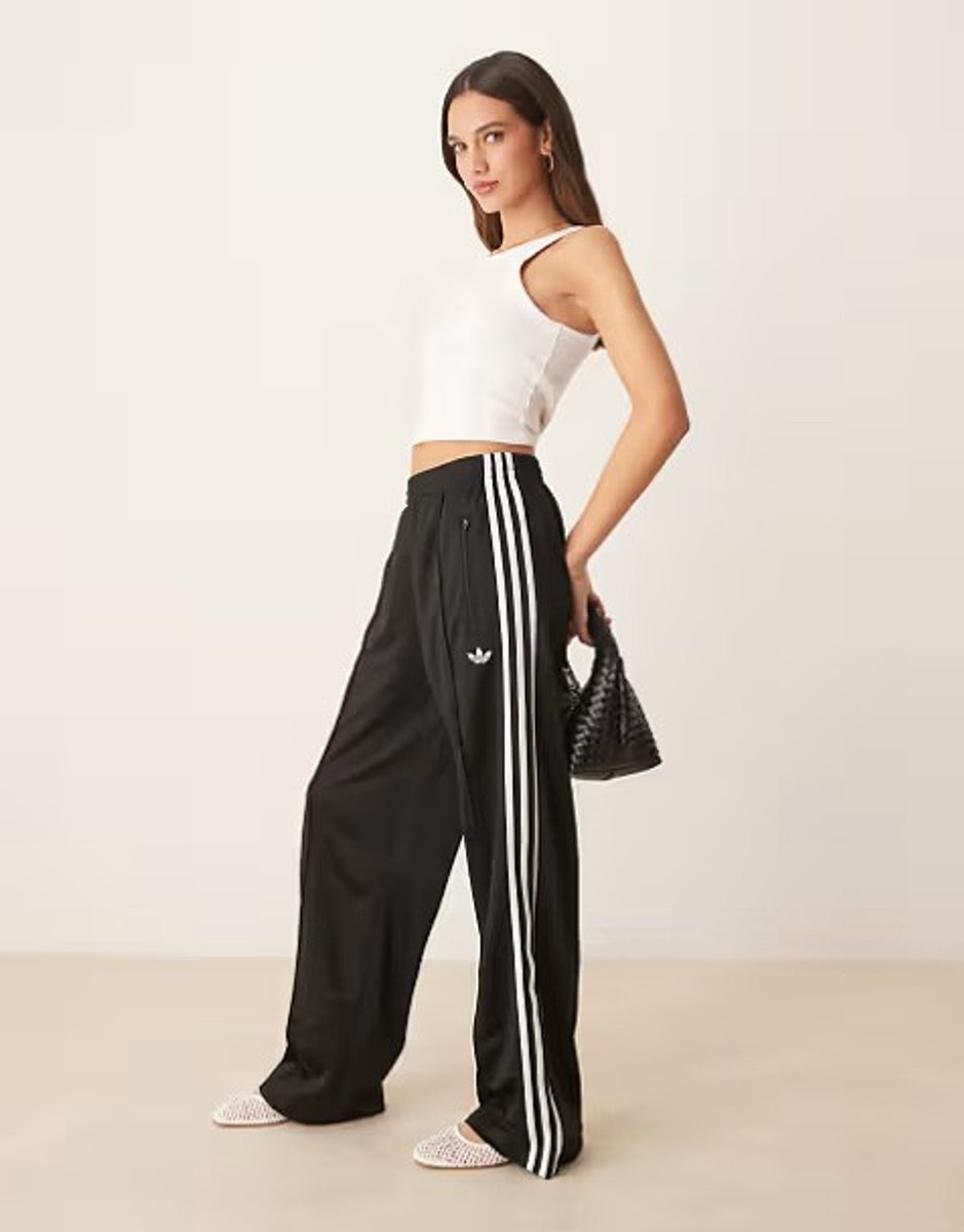 woman wearing loose track pants in black from Adidas