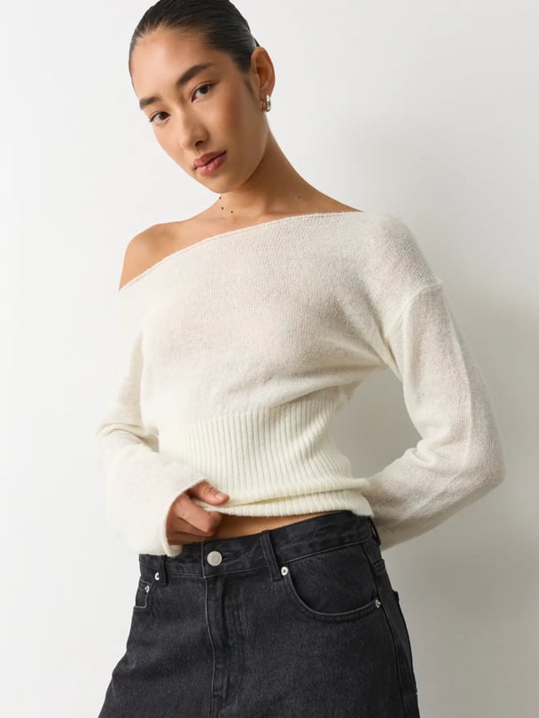 Model in off-shoulder knit top with ribbed waist.