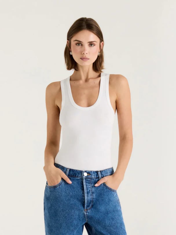 Model wears white scoop tank and blue jeans.
